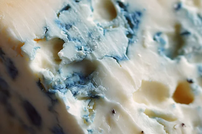 Close-up texture of Masgonzola cheese showing its creamy surface and blue-veined marbling.