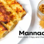 Mannacote sprinkled beside a plate of golden, cheesy manicotti showcasing its crisp texture and perfect baked finish.