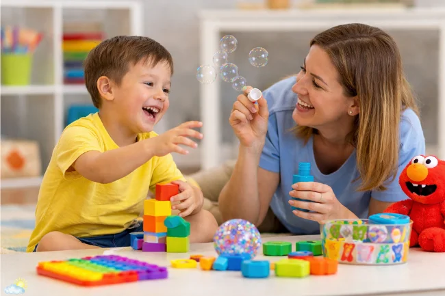 ABA Therapy session using play-based motivation with bubbles, blocks, and sensory toys